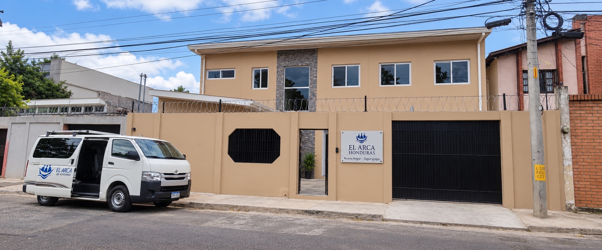 Fachada del nuevo hogar de El Arca Honduras en Tegucigalpa, con el microbús de la comunidad estacionado al frente